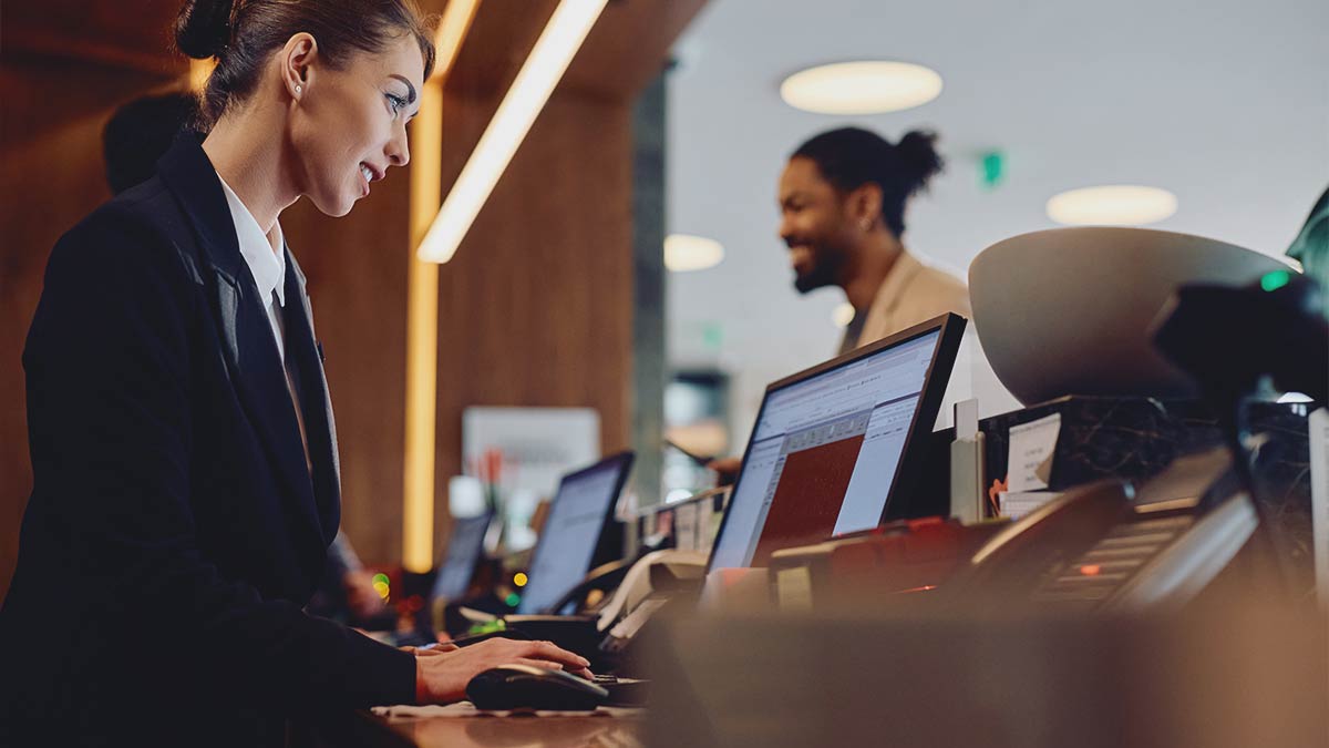 Hotel front desk staff using IT systems with guest interaction – showcasing reliable IT support services for hospitality businesses